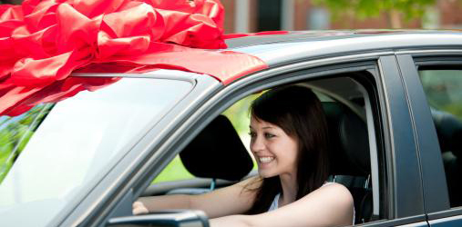 Woman happy in a car with a giant red bow on it