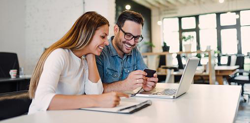 Woman and man looking at computer screen while smiling