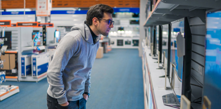 Man looking at a flat-screen tv at a store