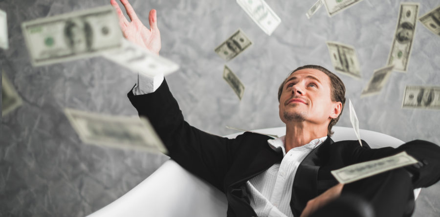 Guy sitting in white chair throwing money in the air