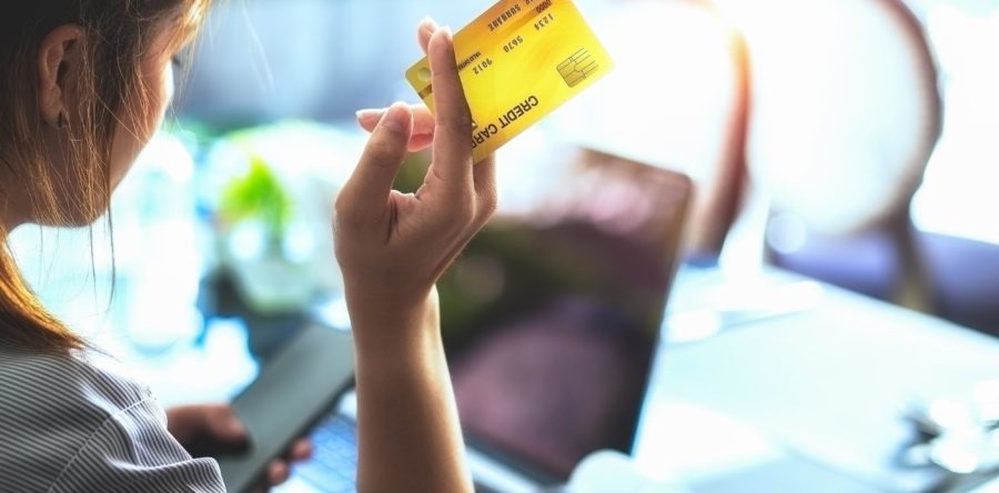 Woman giving someone her credit card while looking at her phone