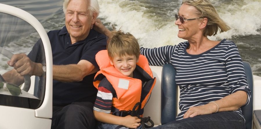 Grandparents with kid with lifejacket on a boat