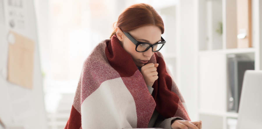Woman wrapped up in a blanket shivering