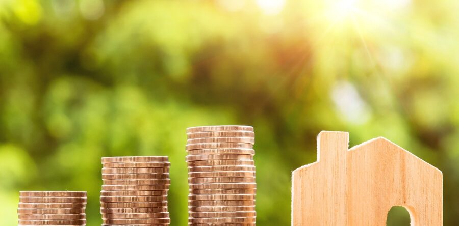 coins stacked up next to a wooden toy house