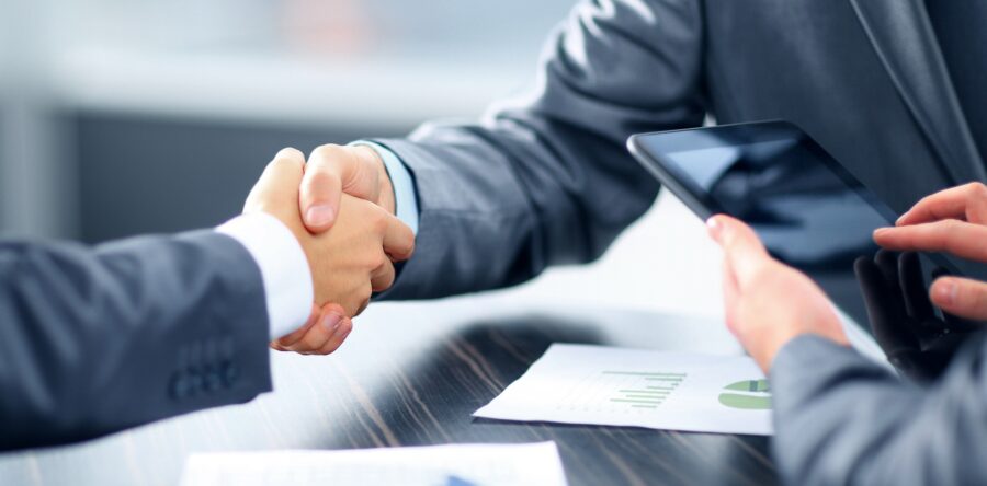 Two Business men shaking hands while another is working on his phone