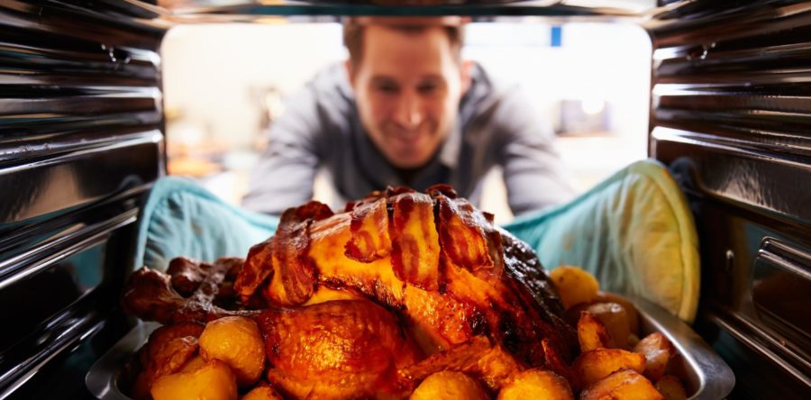 Man pulling out a cooked turkey out of the oven