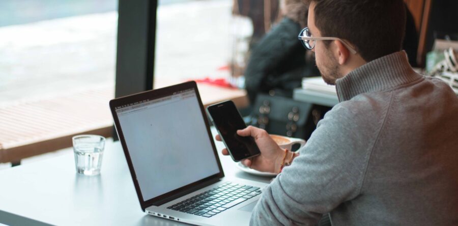 Man looking at his phone and laptop