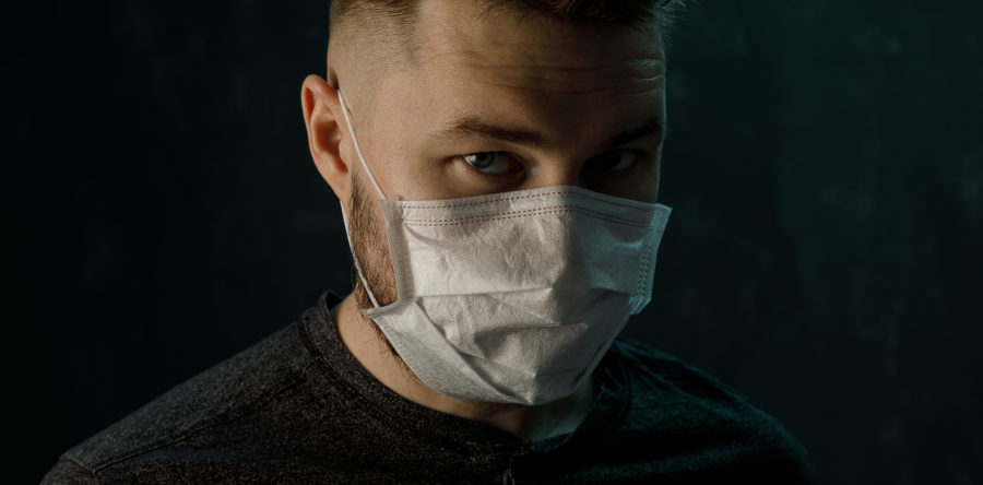 Man in a dark room wearing a surgical Mask