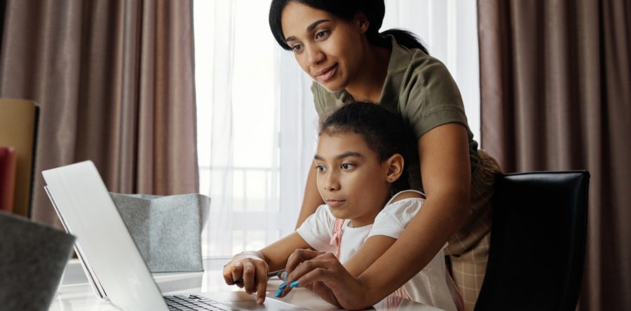 Mom helping her daughter use a laptop