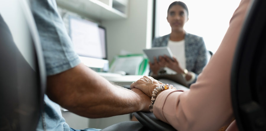 couple holding hands while talking to a doctor